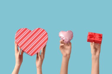 Kalp şeklinde hava balonu ve mavi arka planda hediye kutuları olan kadın elleri. Sevgililer Günü kutlaması