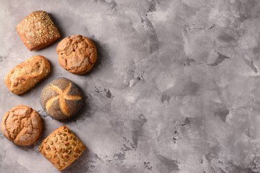 Gri grunge arka planında farklı taze çörekler.