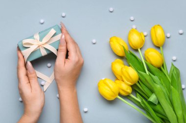 Şimdiki zamana sahip kadın eller ve mavi arka planda laleler