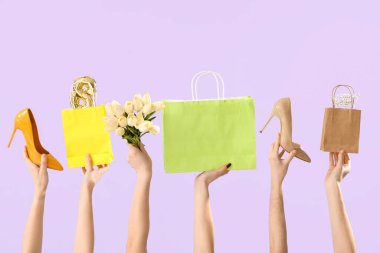 Yüksek topuklu kadın elleri, alışveriş torbaları ve leylak arka planda laleler. Uluslararası Kadınlar Günü