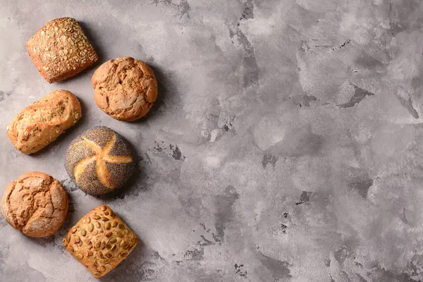 Gri grunge arka planında farklı taze çörekler.