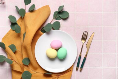 Renkli yumurtalar ve pembe fayanslı okaliptüslerle Paskalya için güzel bir sofra.