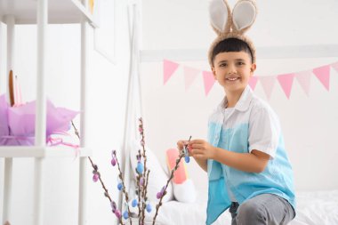 Cute little boy decorating pussy willow branches for Easter celebration at home