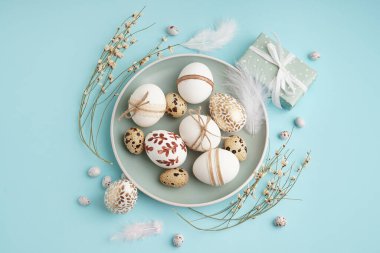 Süslü Paskalya yumurtaları, hediye ve mavi arka planda küçük çiçekler.