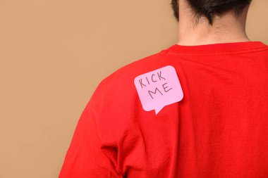 Sırtında kahverengi bir etiket olan yakışıklı bir genç. 1 Nisan kutlamaları