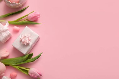 Lale çiçekli Paskalya yumurtaları ve pembe arka planda hediye kutuları.