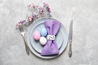 Renkli yumurtalar ve gri grunge arka planda çiçeklerle Paskalya için güzel bir sofra.