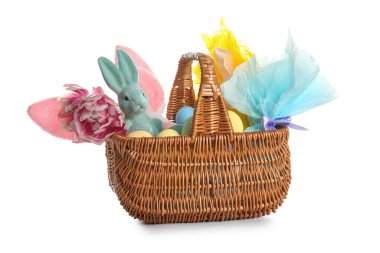 Oyuncak tavşanlı sepet, Paskalya yumurtaları ve beyaz arka planda güzel bir çiçek.