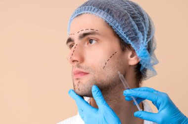 İşaretli yüzü olan genç adam bej arka planda iğne oluyor, yakın plan.