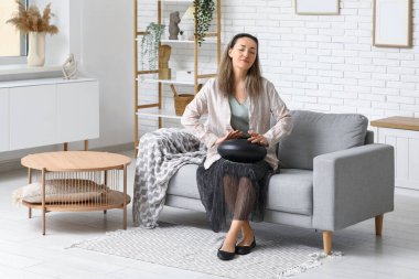 Evdeki kanepede glukofonlu güzel olgun bir kadın.