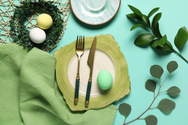 Yumurta, çelenk ve turkuaz arka planda yeşil dallarla Paskalya için güzel bir masa.