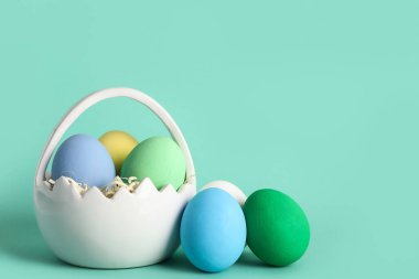 Turkuaz arka planda boyanmış Paskalya yumurtaları olan sepet.