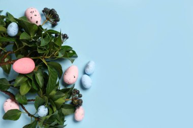 Mavi arka planda yeşil dallı Paskalya yumurtaları