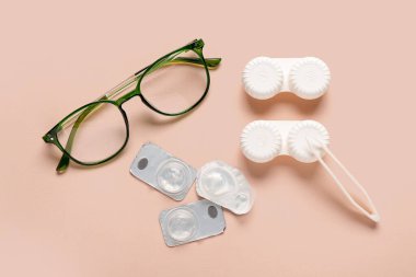 Bej arka planda kontakt lens, gözlük ve cımbızla konteyner