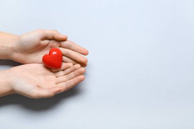 Gri arka planda kırmızı kalpli kadın elleri