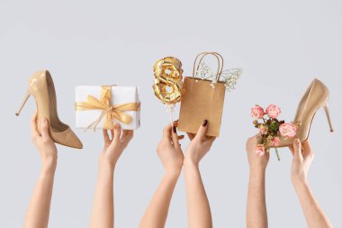 Hediye kutusu, çiçekler ve beyaz arka planda yüksek topuklu ayakkabılar olan kadın elleri. Uluslararası Kadınlar Günü için Alışveriş