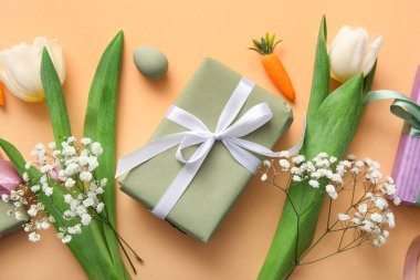 Turuncu arka planda Paskalya kutlaması için çiçek ve hediye kutusu