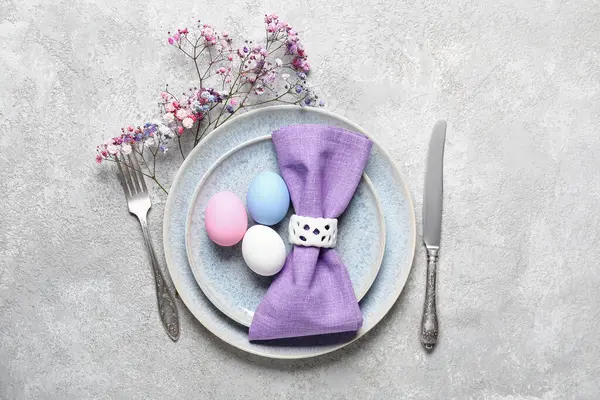 Renkli yumurtalar ve gri grunge arka planda çiçeklerle Paskalya için güzel bir sofra.