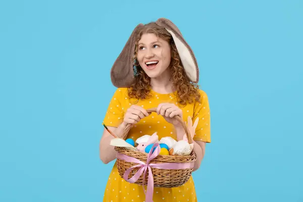 Piękna Młoda Szczęśliwa Kobieta Króliczych Uszach Koszykiem Wielkanocnym Niebieskim Tle — Zdjęcie stockowe