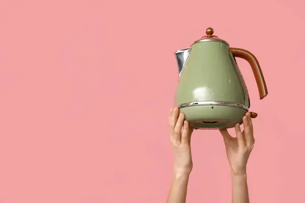 Woman with electric kettle on pink background