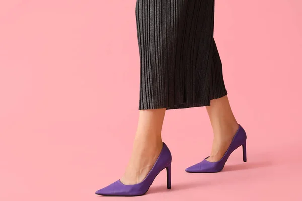 Legs of young woman in stylish purple high heels on pink background