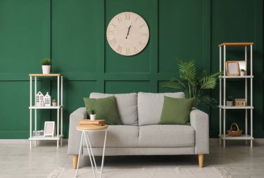 Rahat kanepesi, çiçekleri, masası, saati ve rafları olan şık bir oturma odası.