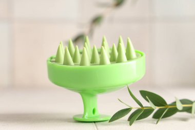 Hafif arka planda okaliptüslü silikon kafa masajı fırçası, yakın plan.