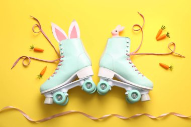 Sarı arka planda kağıt ve havuçtan yapılmış tavşan kulaklı klasik patenler. Paskalya kutlaması