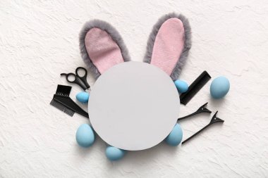 Paskalya yumurtalı tavşan kulakları, kuaför aletleri ve beyaz grunge arka planda boş tebrik kartı.