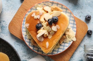 Kalp şeklinde lezzetli gözlemeler, mavi arka planda yabanmersini ve fındık, yakın plan. Sevgililer Günü kutlaması