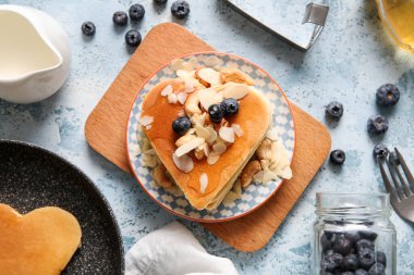 Kalp şeklinde lezzetli krepler, mavi arka planda yabanmersini ve fındıklı. Sevgililer Günü kutlaması