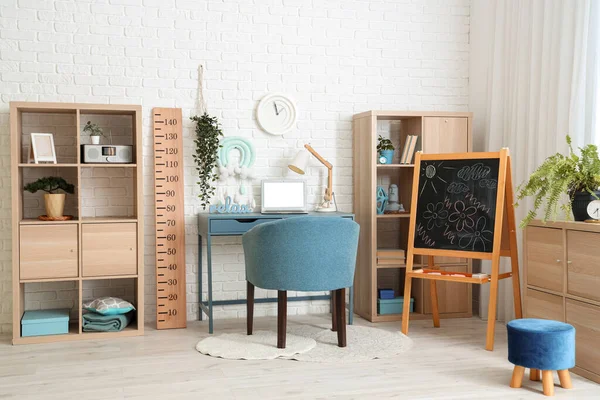 Rahat çalışma alanı, dizüstü bilgisayarı ve ahşap stadyumu olan modern çocuk odası.