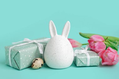 Paskalya hediyeleri, tavşan figürü ve mavi arka planda laleler.