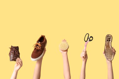 Ayakkabı parçaları, makas ve sarı arka planda fırçayla kadın elleri. Ayakkabı tamir konsepti