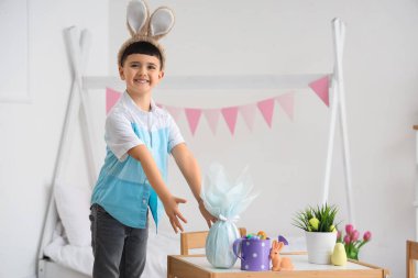 Paskalya hediyesi yumurta ve süslemelerle tavşan kulağı takan şirin bir çocuk.