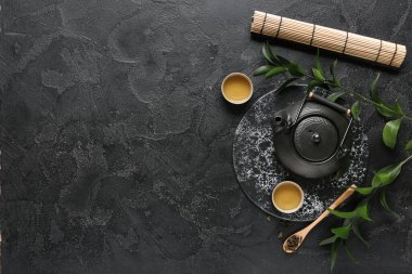 Çaydanlık, bir fincan sıcak çay ve siyah yapraklı kaşık.