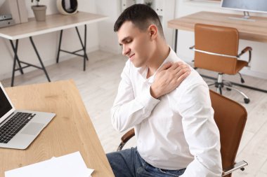 Genç işadamı ofiste omuz ağrısı çekiyor.