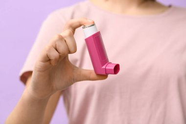 Leylak arka planında astım spreyi olan çocuk, yakın plan.