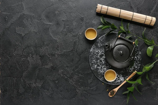 Çaydanlık, bir fincan sıcak çay ve siyah yapraklı kaşık.