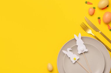Güzel Paskalya sofrası. Sarı arka planda yumurtalar, oyuncaklar ve tavşanlarla servis ediliyor.