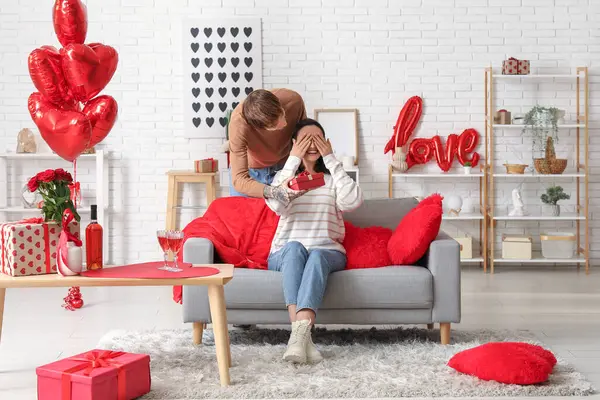 Genç adam sevgilisini sevgililer gününde evde karşılıyor.