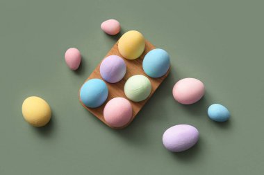 Yeşil arka planda boyanmış Paskalya yumurtaları olan tahta tutucu.