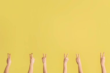 Sarı arka planda barış hareketlerini gösteren kadın elleri