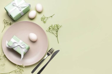 Yeşil arka planda hediyeler, çiçekler ve yumurtalarla güzel bir Paskalya masası.