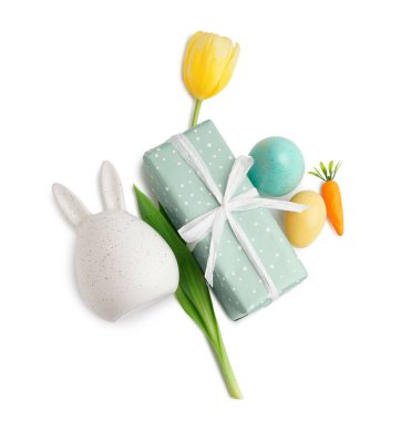 Paskalya tavşanı, boyalı yumurta, lale ve beyaz arka planda hediye.