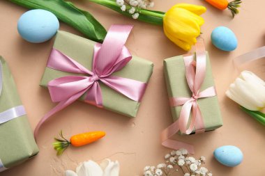 Paskalya yumurtaları hediye kutuları ve bej arka planda çiçekler.
