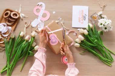 Kadın hediye paketi, tebrik kartı ve ahşap arka planda lale çiçekleri. Uluslararası Kadınlar Günü