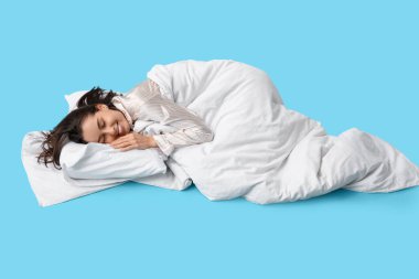 Battaniyeli, mavi arka planda uyuyan güzel genç bir kadın.