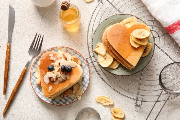 Kalp şeklinde lezzetli gözlemeler, hafif arka planda kurutulmuş muz ve yabanmersini tabakları. Sevgililer Günü kutlaması