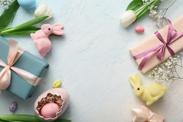 Hediye kutularıyla Paskalya yumurtaları ve mavi grunge arka planda tavşanlar.